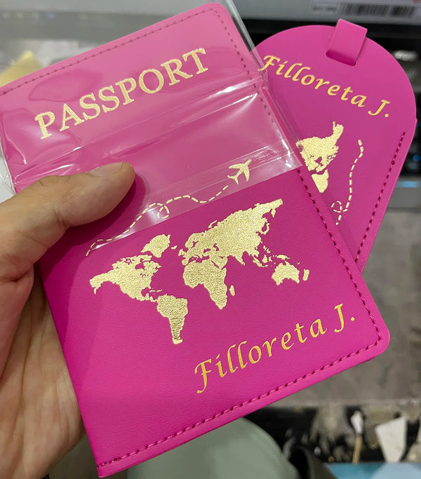 A pink passport cover with gold foil printing and a matching luggage tag is held in a hand.