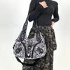 A woman holds a leopard print crossbody shoulder bag with multiple compartments against a white background.
