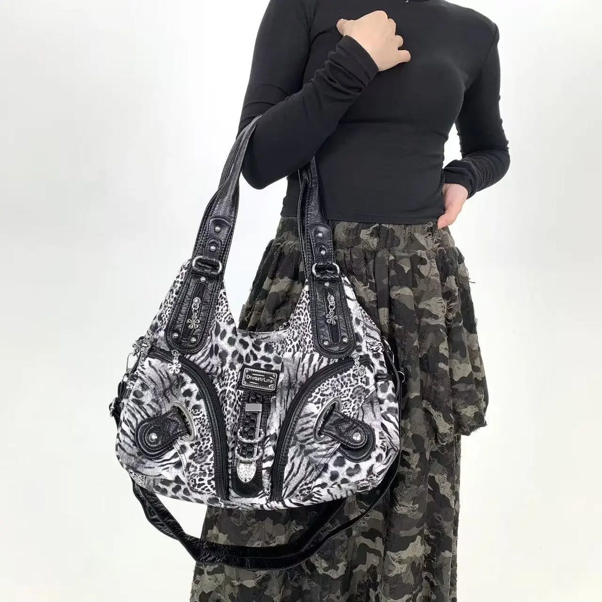 A woman holds a leopard print crossbody shoulder bag with multiple compartments against a white background.