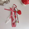A red and white lace bag charm keychain featuring a strawberry pendant and decorative ribbons.
