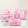 Pink quilted cotton makeup organizer set with a checkered pattern displayed on white blocks.