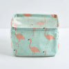 A light mint green storage basket with a repeating pattern of pink flamingos for desk organization.