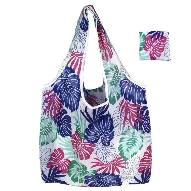 A reusable fashion shopping tote bag featuring a vibrant tropical leaf print in shades of purple, green, and white.