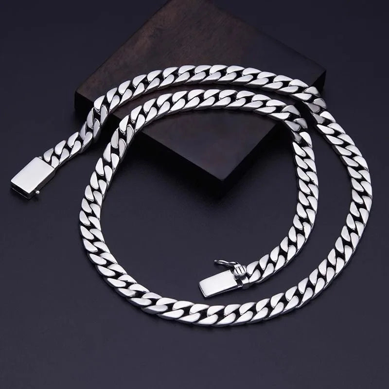 A silver punk charm bracelet with a padlock clasp is displayed on a dark surface.