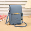 A light blue leather crossbody bag with gold hardware resting on a tan surface.