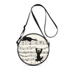 A round crossbody bag featuring a cartoon cat design and musical notes.