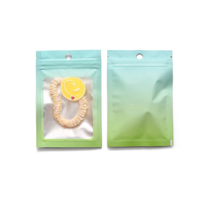 Two light green gradient resealable storage bags, one containing a yellow necklace.