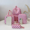 A pink and white checkerboard multi-pocket backpack with a matching pouch and a small wallet on a white surface.
