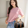 A young woman models a pink sweater and blue jeans while holding a brown and black leather shoulder crossbody bag.
