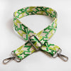 A wide crossbody bag strap featuring a green and beige letter M jacquard pattern.