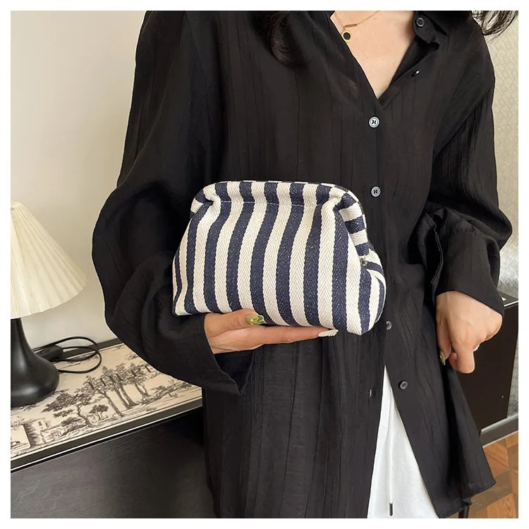 A woman holds a striped black and white crochet handbag against a black shirt.