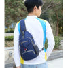 A person wearing a white long-sleeved shirt and jeans is holding a navy blue nylon chest sling bag.
