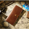 A brown genuine leather long bi-fold wallet with a snap closure resting on an old map background.