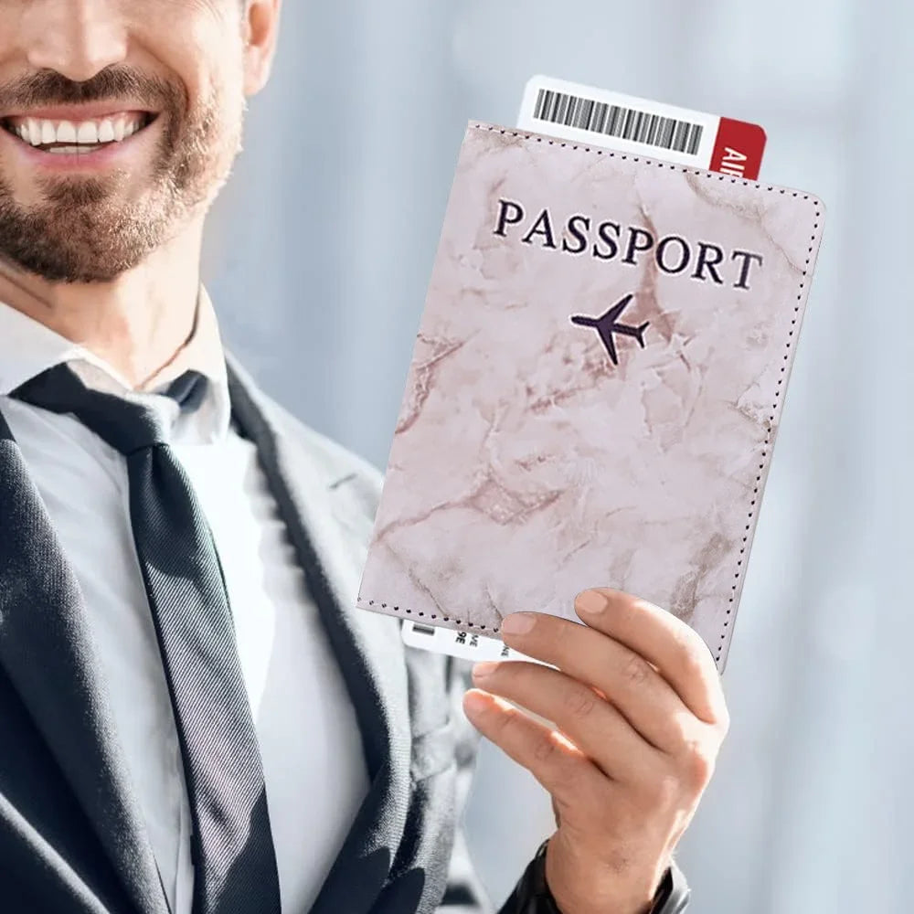 Un hombre de traje sostiene una funda de pasaporte rosa con un emblema de avión negro y una tarjeta de identidad.