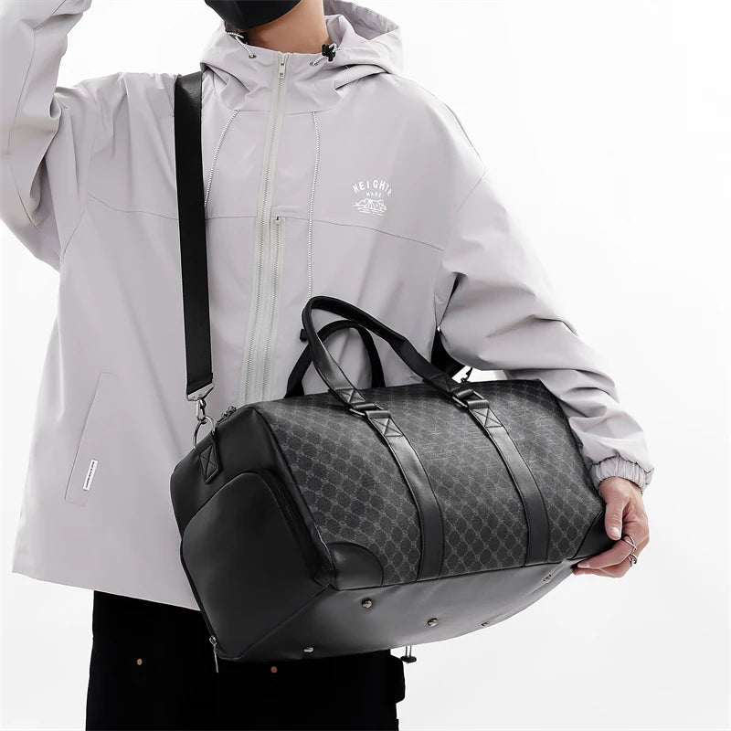 A person wearing a light gray hooded jacket holds a black leather-trimmed travel duffle bag.