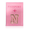 A pink leather passport holder with a gold initial N embossed on the front.