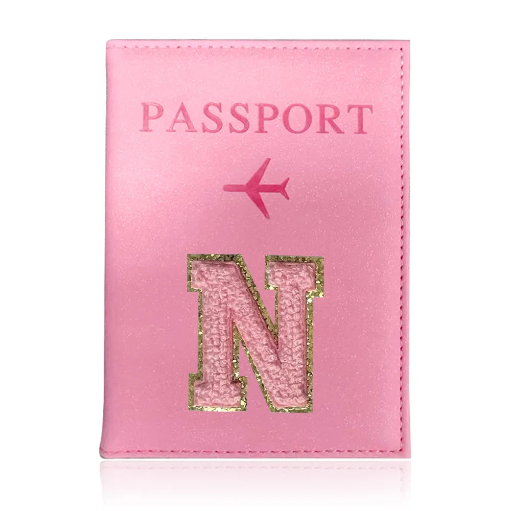 A pink leather passport holder with a gold initial N embossed on the front.