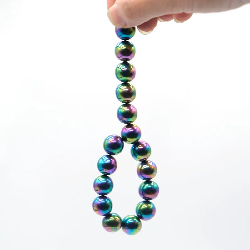 Eine Hand hält eine Kette aus irisierenden, farbenfrohen Glasperlen als Stressabbauarmband.