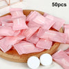 Une pile de serviettes faciales en coton compressé roses réutilisables sur un plateau en bois.