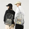 A person is holding a waterproof transparent backpack with a clear plastic design and various items inside.
