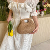 Une femme portant une robe blanche tient un sac à main en paille tressée.