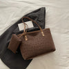 A brown leopard print tote bag is shown resting on a dark gray blazer or jacket on a white surface.