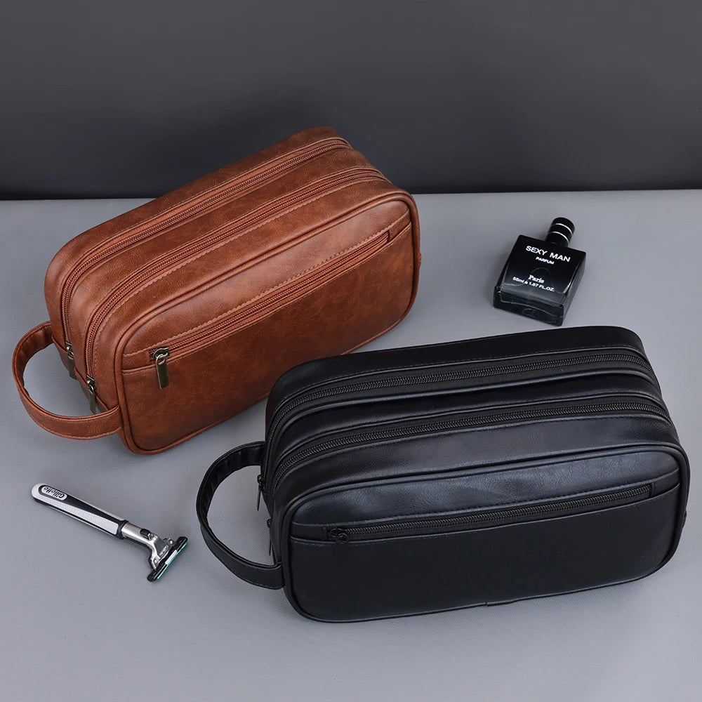 A brown leather toiletry bag and a black leather grooming pouch are displayed on a gray surface.