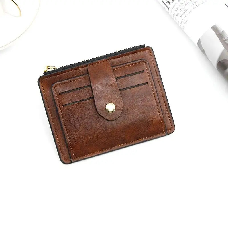 A brown leather card holder wallet with a flap and coin pocket is shown on a white background.