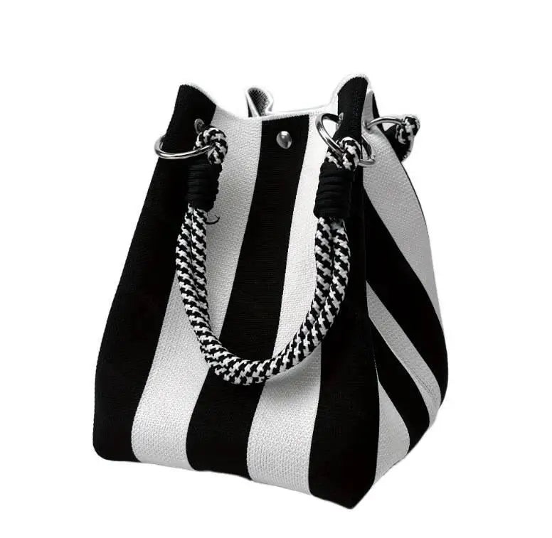 A black and white striped knit bucket tote bag with silver hardware.