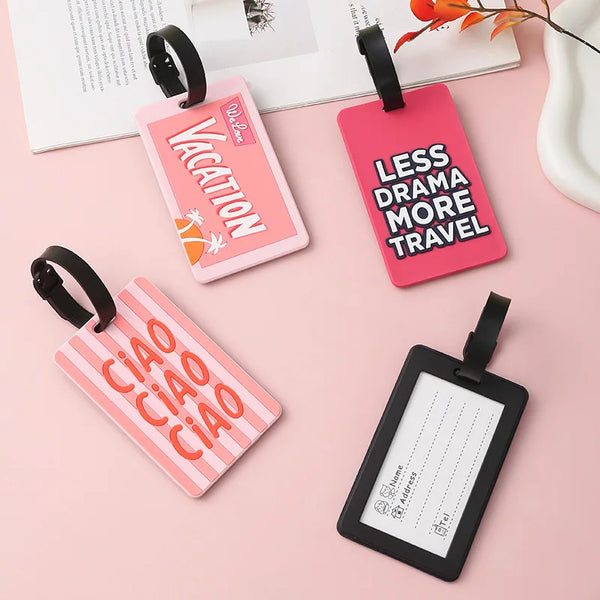 A collection of pink and black silicone letter luggage tags with various designs like Vacation and Less Drama More Travel