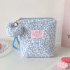 A light blue leopard print makeup bag with a fluffy trim and gold hardware.