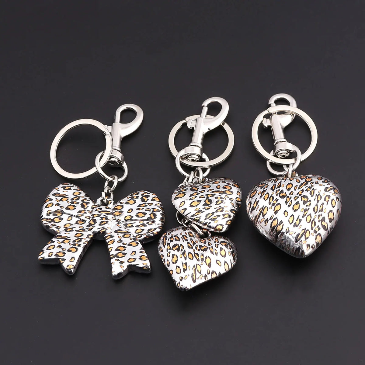 Silver bag charm keychain featuring a leopard print bow and heart charms