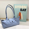 A light blue storage shoulder bag is displayed next to a book titled Byron Bay.