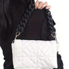 White quilted leather handbag with a black chunky chain shoulder strap being held by a person.