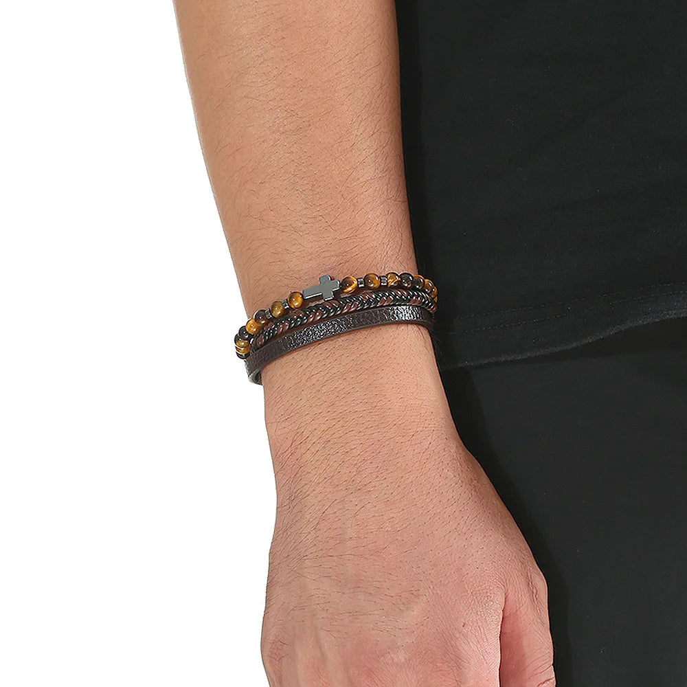A men's multi-layer leather bracelet featuring tiger eye beads worn on a wrist against a black background.