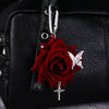 A realistic red rose flower keychain with a silver cross and a white butterfly attached to a black leather bag.