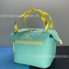 A light mint green insulated lunch bag with a yellow strap is shown against a gray background.