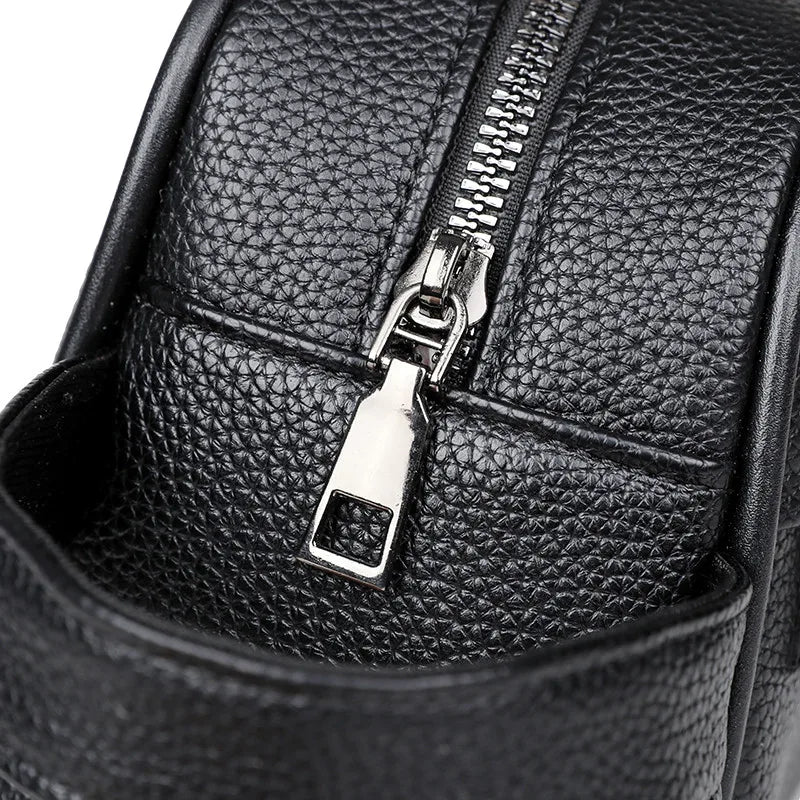 Close-up of a black PU leather clutch bag featuring a silver zipper detail.