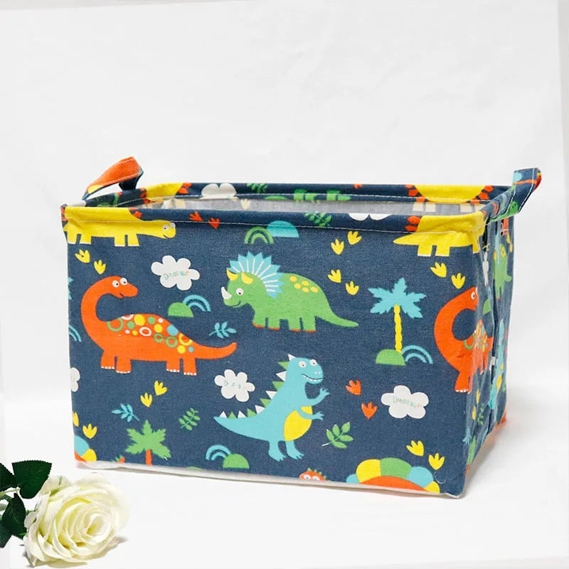 A blue fabric storage basket with a dinosaur pattern and yellow trim, featuring handles.