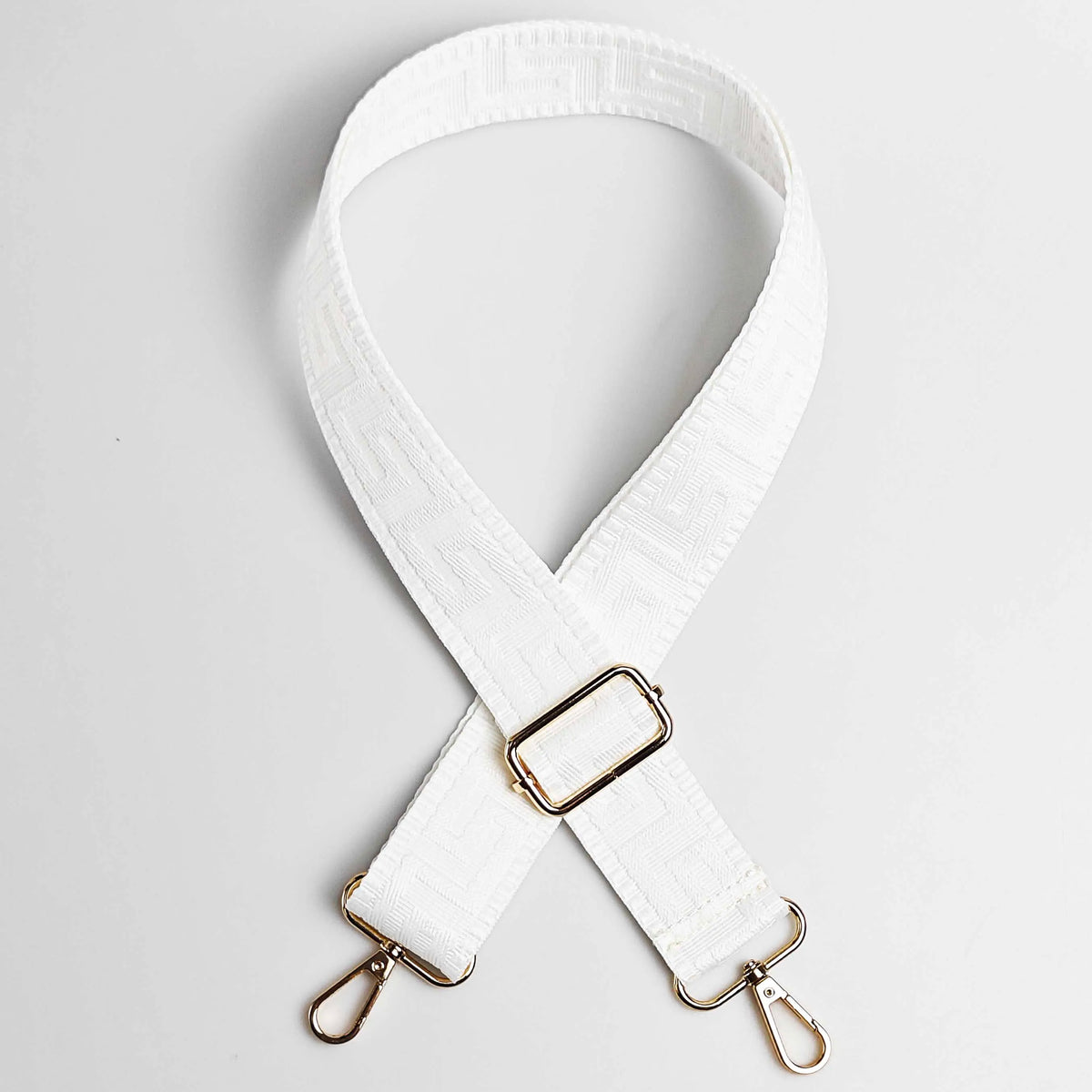 White adjustable crossbody bag strap with a maze pattern and gold-toned hardware