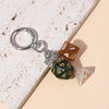 A silver keychain charm featuring various colored dice, including amber, green, and white.
