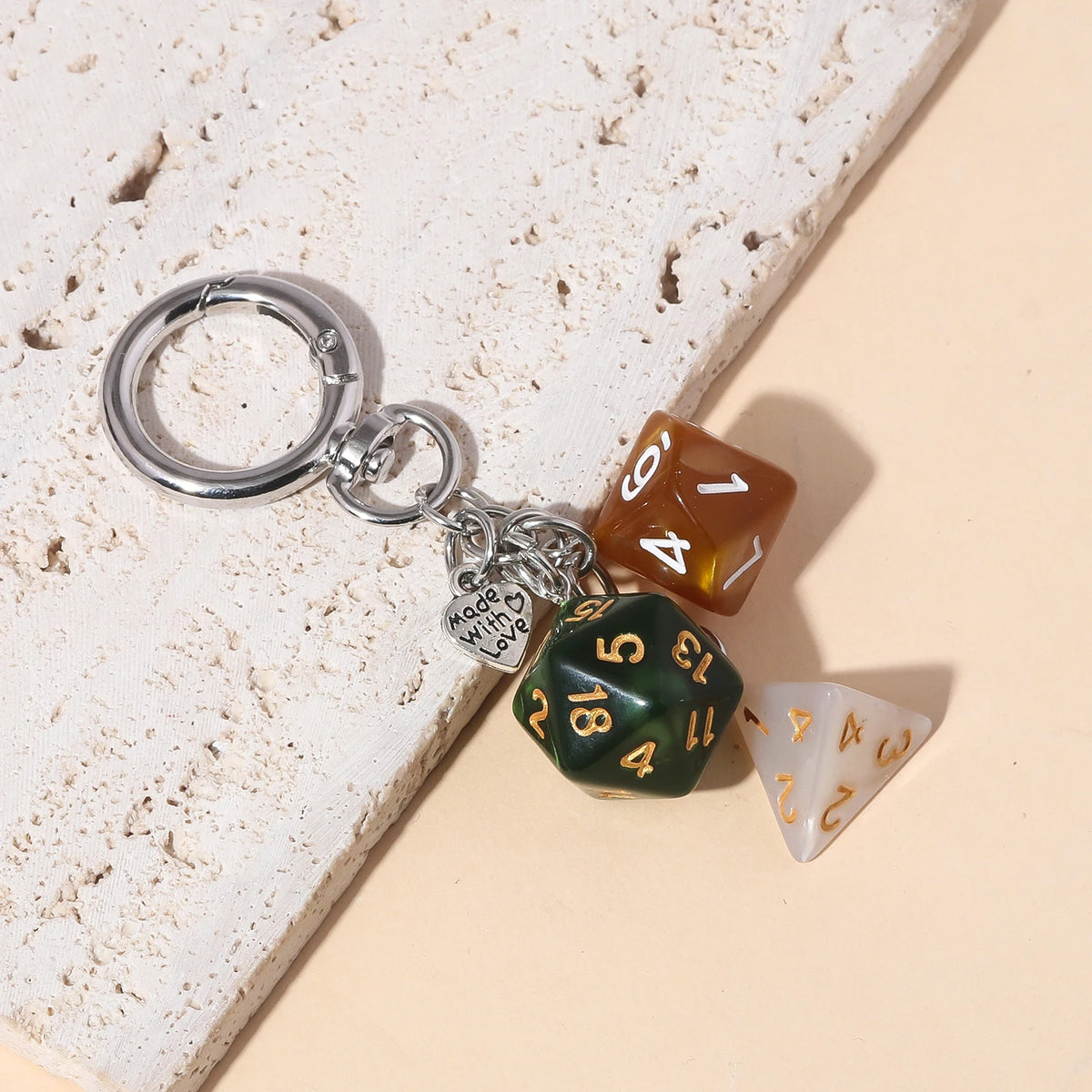 A silver keychain charm featuring various colored dice, including amber, green, and white.