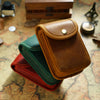 A brown leather multi-functional waist bag resting on a map background with other leather goods.