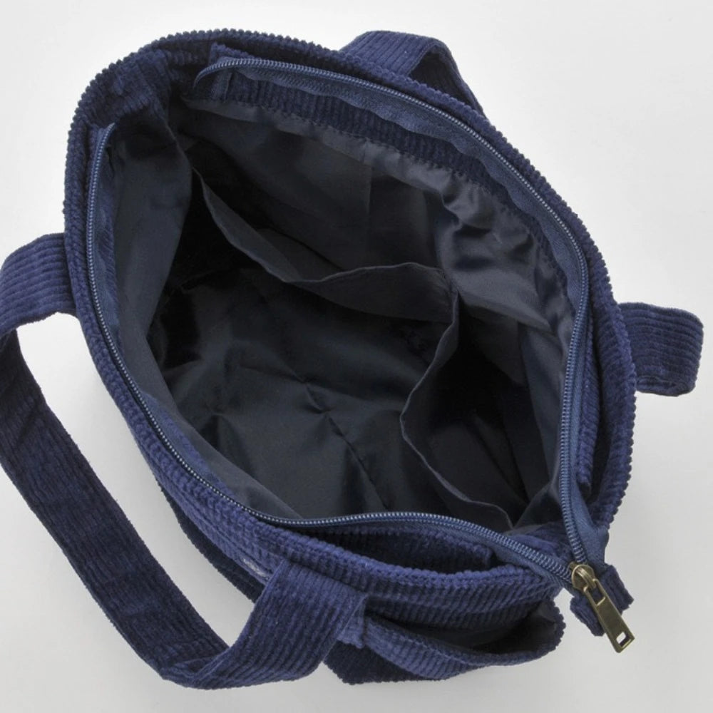 A dark blue canvas shoulder bag with a zipper, shown open and folded.