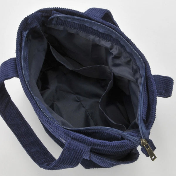 A dark blue canvas shoulder bag with a zipper, shown open and folded.