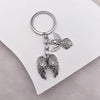 Silver metal angel wing keychain charm with a circular keyring