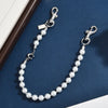 A delicate pearl and gold letter charm necklace displayed on a dark blue velvet surface.