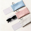 A set of polka dot eyeglass pouches in light blue, pink, and white with metal keychains.