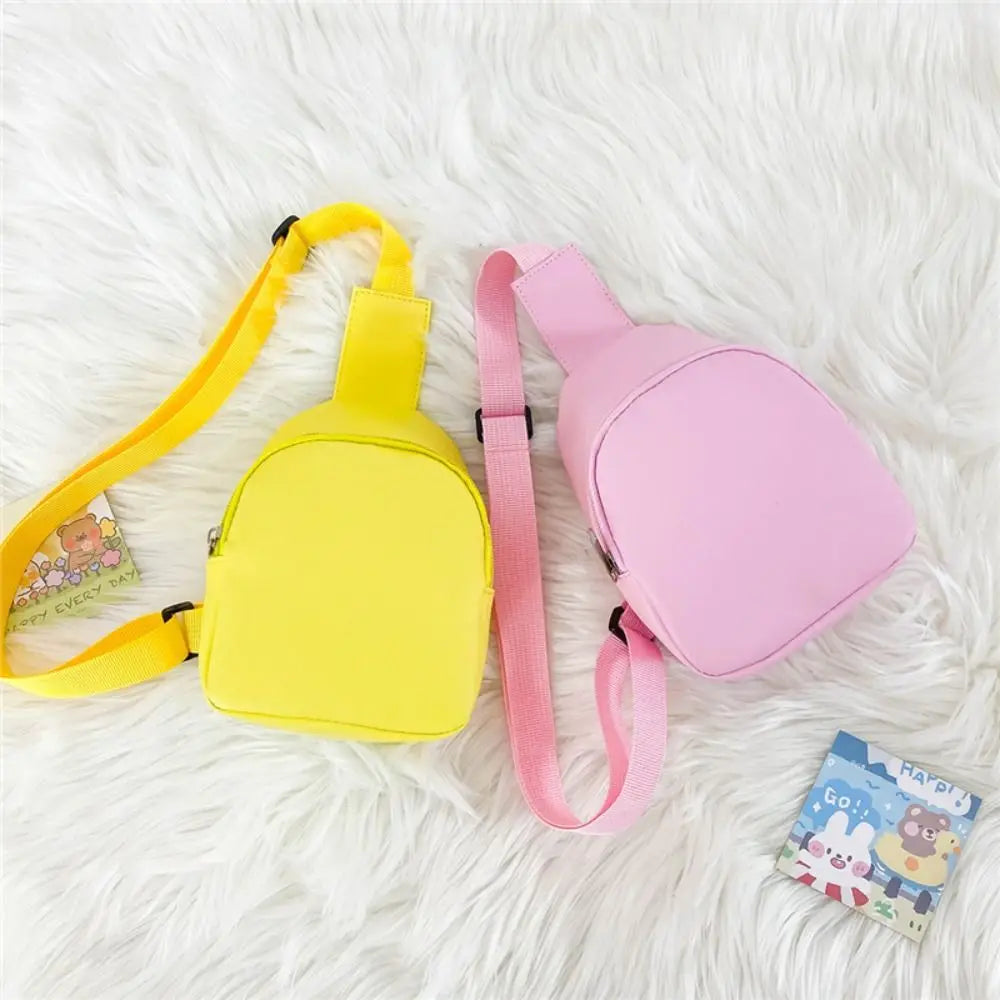 A yellow and pink nylon crossbody bag for kids lying on a white fluffy surface.