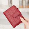 A close-up of a red quilted PU leather bifold wallet with a zipper, held by a hand.